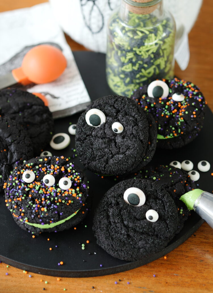 Black velvet cookie sandwiches filled with green buttercream and decorated with colorful Halloween sprinkles.