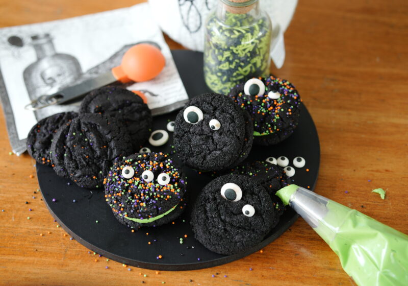 Black velvet cookie sandwiches filled with green buttercream and decorated with colorful Halloween sprinkles.