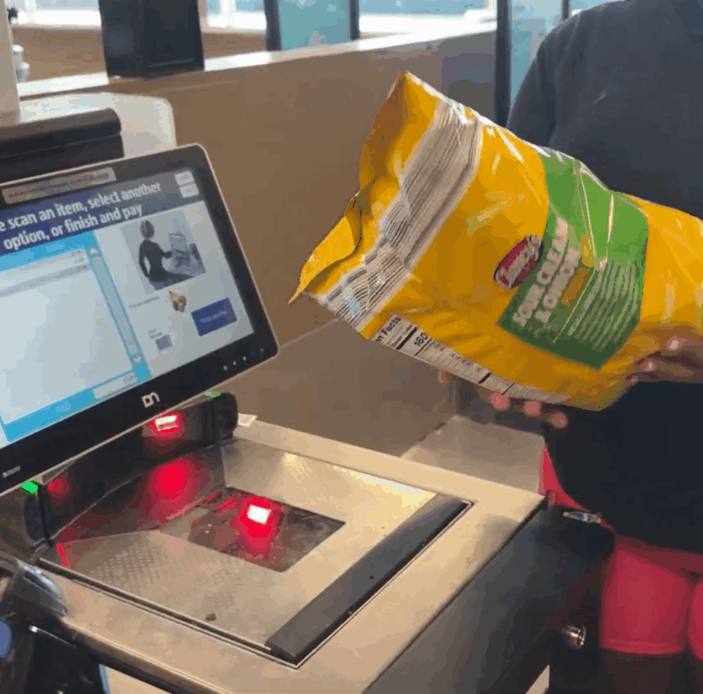 Homeschooling and working from home mom’s daughter scanning groceries at Aldi self-checkout, learning responsibility during a shopping trip.