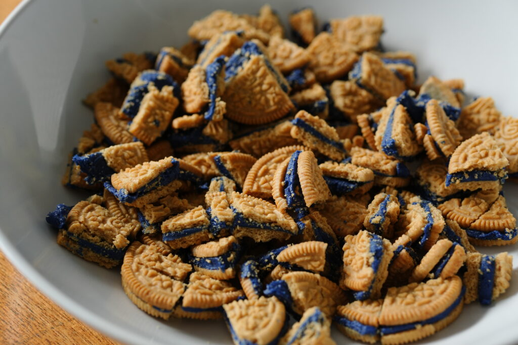 Bowl of chopped blueberry Oreo cookies ready to be added to white chocolate chip blueberry pie cookie dough.