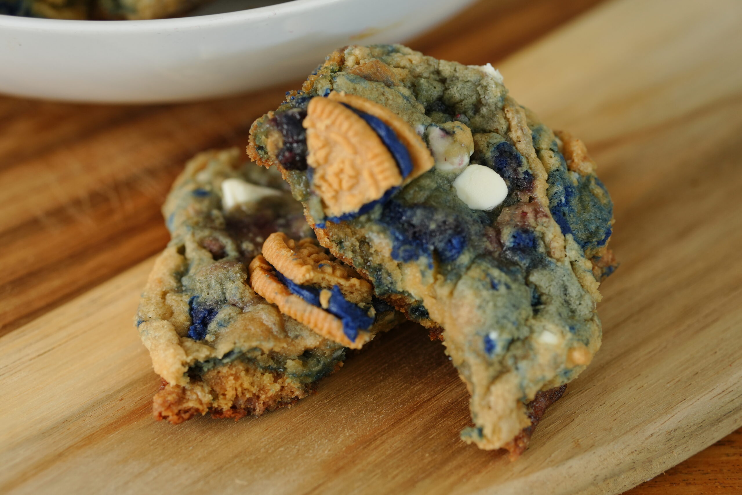 Close-up of white chocolate chip blueberry pie cookies loaded with blueberry jam swirls and Oreo cookie pieces in a bowl.