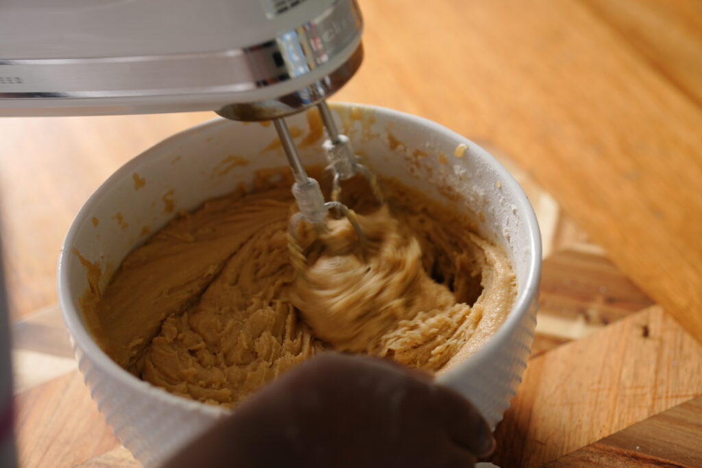 Bowl with melted butter, dark brown sugar, and white sugar being mixed for cookie bar dough.