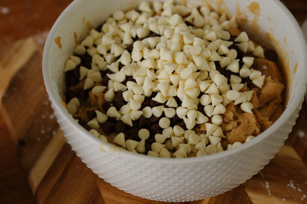 Mixing chocolate chips into prepared cookie dough batter.