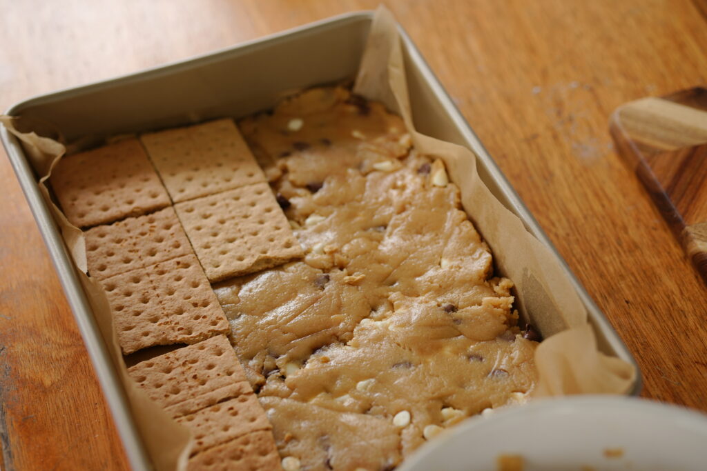 Graham crackers placed evenly over cookie dough base in pan.