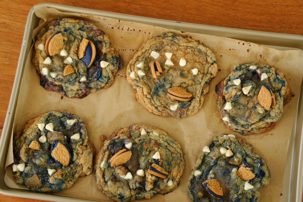 Freshly baked white chocolate chip blueberry pie cookies cooling on a baking sheet.