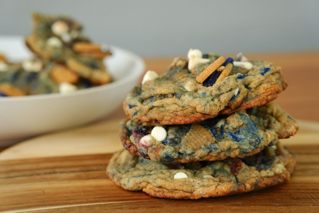 Stack of freshly baked white chocolate chip blueberry pie cookies with Oreos and blueberries.