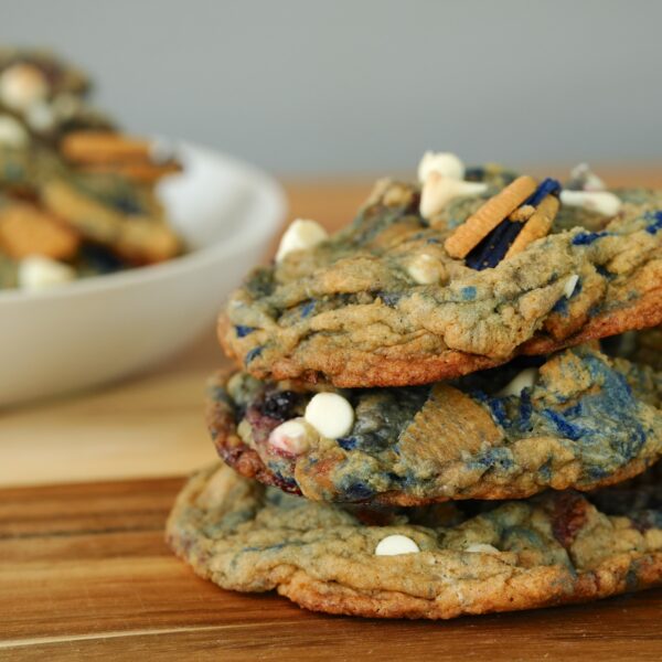 Stack of freshly baked white chocolate chip blueberry pie cookies with Oreos and blueberries.