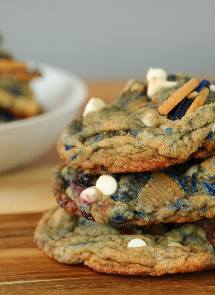 Stack of freshly baked white chocolate chip blueberry pie cookies with Oreos and blueberries.