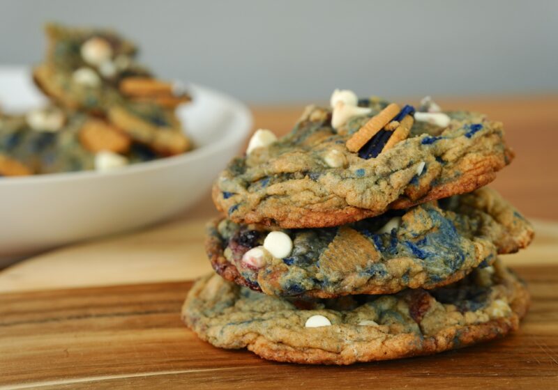 Stack of freshly baked white chocolate chip blueberry pie cookies with Oreos and blueberries.