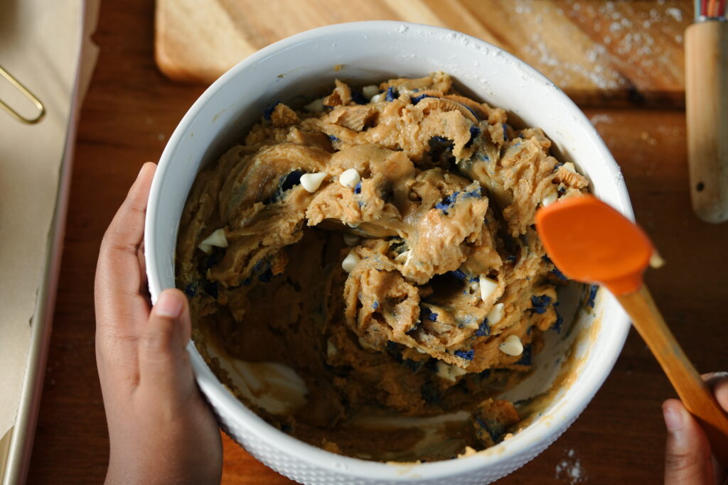 Bowl of thick white chocolate chip blueberry pie cookie dough with Oreo pieces.