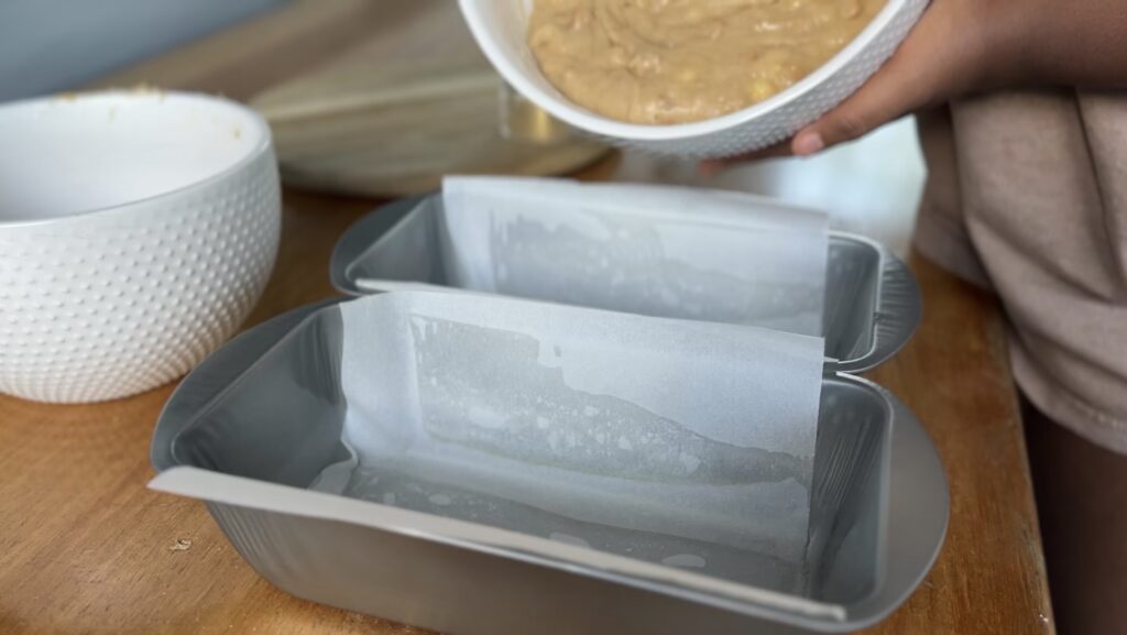 Lined loaf pans ready for butterscotch banana bread batter – parchment paper overhang for easy bread removal