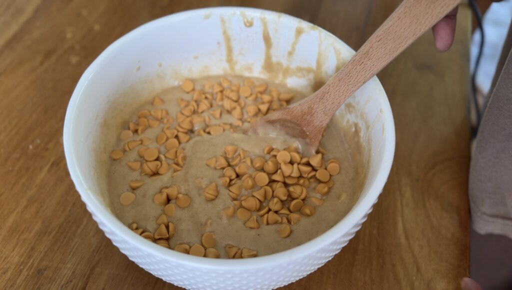 Butterscotch chips sprinkled into banana bread batter – ready to be folded in for an even distribution