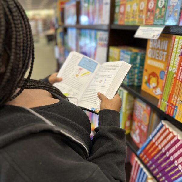 Teen reading and holding a book in Big Fat Notebook series in the homeschool section of a bookstore.
