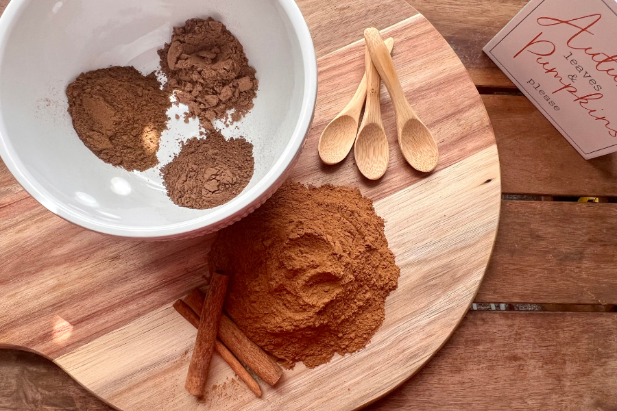 Ingredients for homemade pumpkin pie spice separated on a cutting board – ground cinnamon, nutmeg, allspice, and cloves ready for mixing