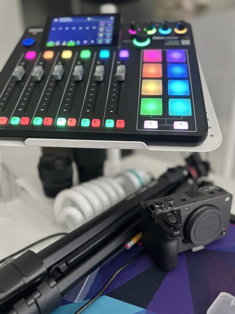 Colorful podcast batching setup with Rodecaster Pro, Sony camera, tripod, and lighting equipment on a desk