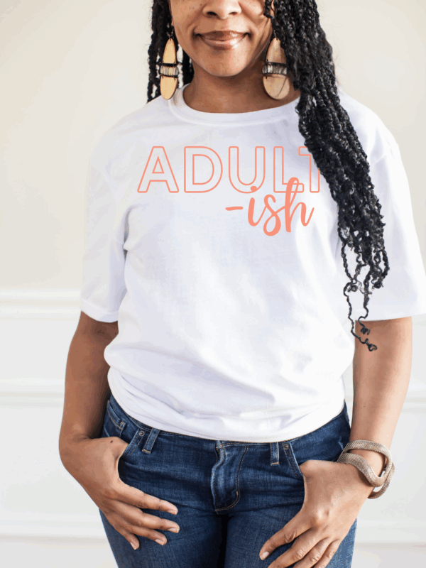 Woman wearing a white “Adult-ish” t-shirt styled with jeans.