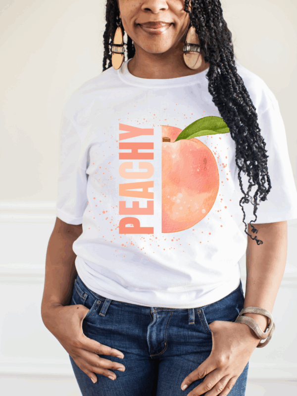 Woman wearing white Peachy Graphic Tee with jeans and hat