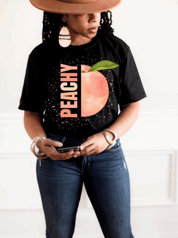 Woman styling black Peachy Graphic T-Shirt with jeans and hat